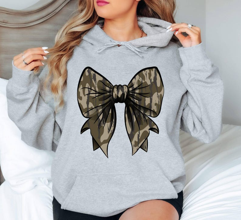 May include: A gray hooded sweatshirt with a large camouflage bow on the front.