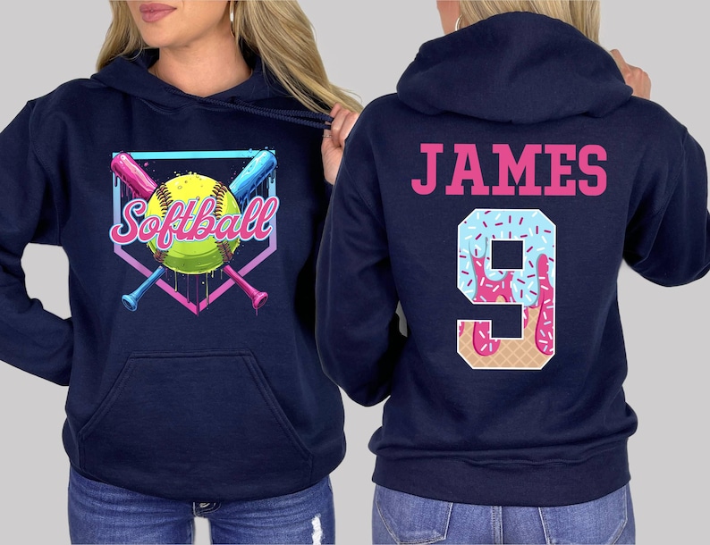 May include: Two navy blue hooded sweatshirts. One sweatshirt has a graphic of a softball with crossed bats and the text "Softball". The other sweatshirt has the text "JAMES" and the number "9" with a pink and blue ice cream cone design.