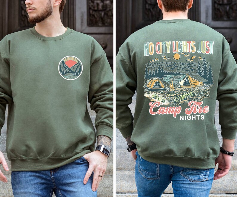 May include: A green sweatshirt with a graphic of a mountain scene and the text "No city lights just camp fire nights" on the back. The front of the sweatshirt has a smaller graphic of a mountain scene.