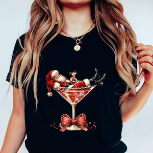 May include: A black t-shirt with a graphic of Santa Claus relaxing in a martini glass. The glass is filled with a red liquid and has a red bow on the stem.