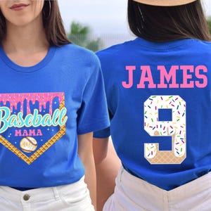 May include: Two blue t-shirts, one with a baseball-themed design that says "Baseball Mama" and the other with the name "JAMES" and the number "9" in a white and pink ice cream cone design.
