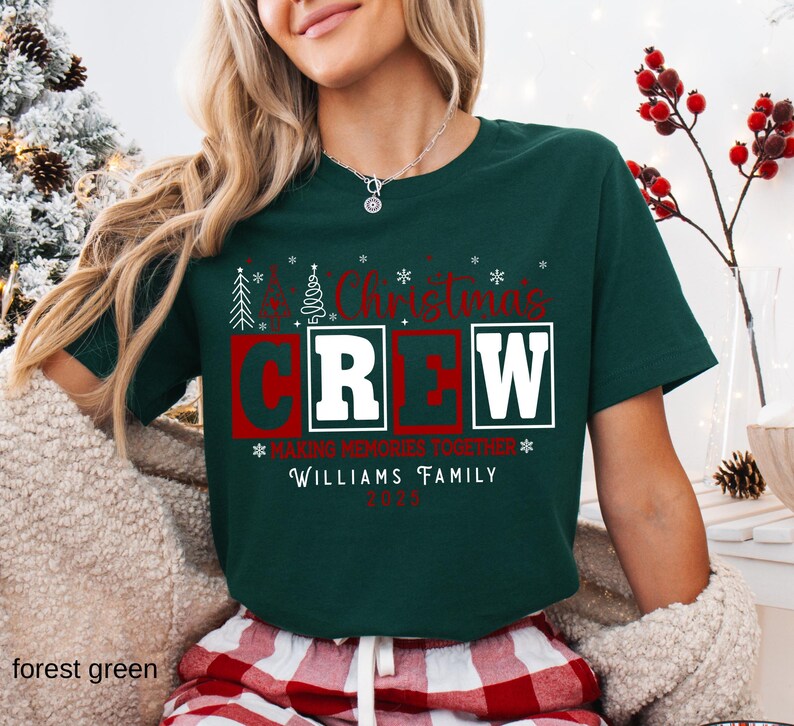 May include: A forest green Christmas Crew t-shirt with red and white text. The text includes "Christmas Crew", "Making Memories Together", "Williams Family", and the year 2023. The shirt has a crew neck and short sleeves.