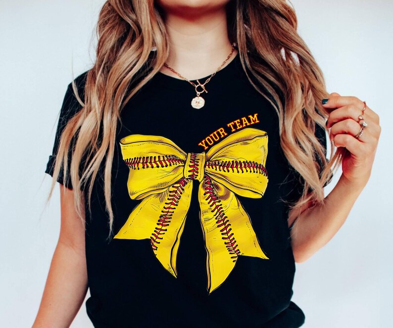 May include: Black t-shirt with a yellow and red softball bow and the text "Your Team" printed on the front.