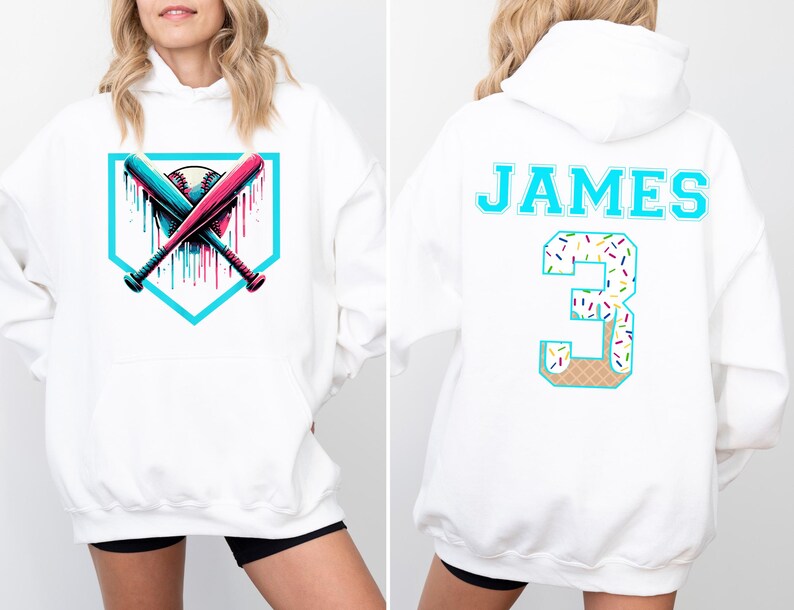 May include: White hoodie featuring a baseball design with crossed bats and a baseball. The back of the hoodie has the name "JAMES" and the number "3" in a teal color with a sprinkle and waffle cone design.