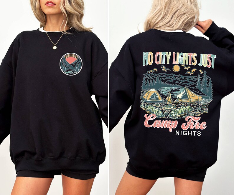 May include: Black sweatshirt with a graphic print of a mountain scene and the text "No city lights just camp fire nights" on the back. The front of the sweatshirt has a smaller graphic of a mountain scene.