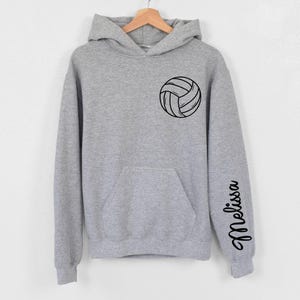 May include: Gray hooded sweatshirt with a black volleyball graphic on the front and the name "Melissa" written vertically on the left sleeve.