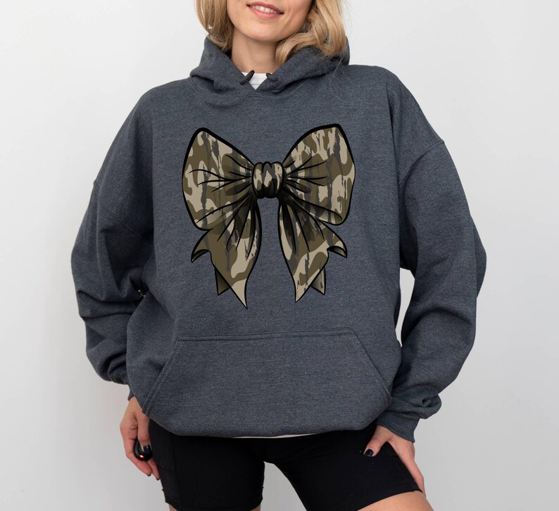 May include: A dark gray hooded sweatshirt with a camouflage bow design on the front.