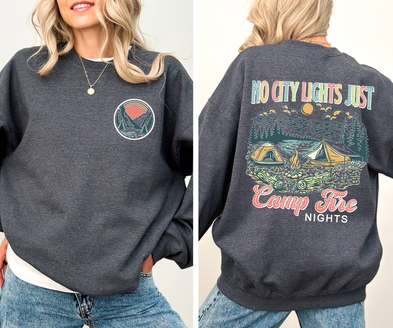 May include: A dark gray sweatshirt with a graphic print of a mountain scene and the text "NO CITY LIGHTS JUST CAMP FIRE NIGHTS". The front of the sweatshirt has a smaller graphic of a mountain scene.