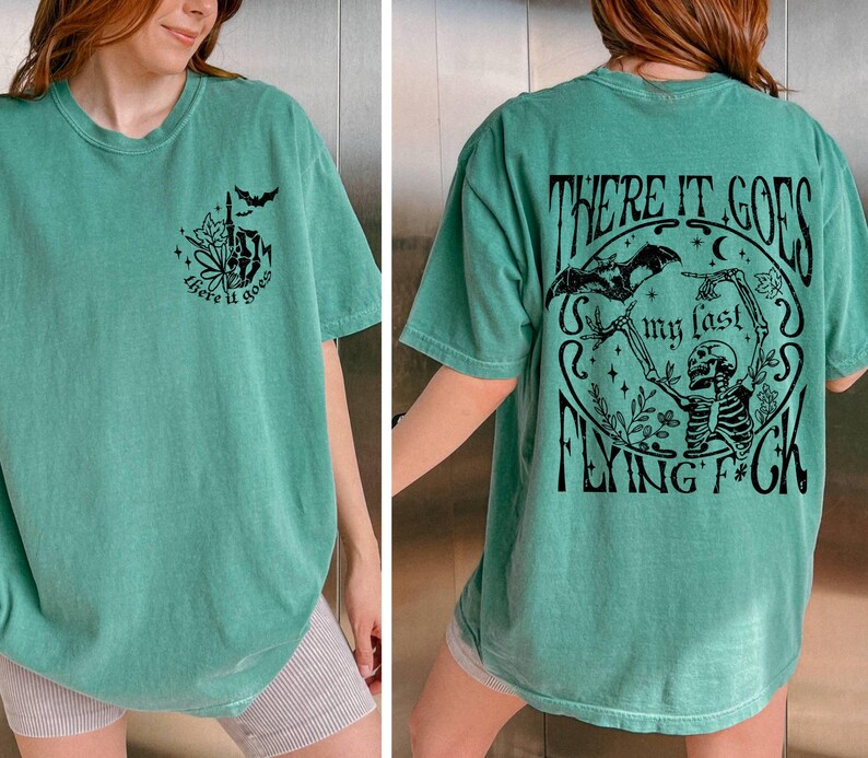 K&ouml;nnte beinhalten: Ein gr&uuml;nes T-Shirt mit einem Skelett-Motiv und dem Text "There it goes my last flying f*ck".