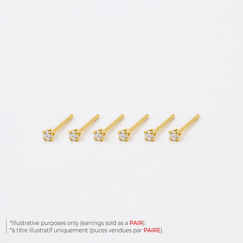 May include: Six gold-colored stud earrings with a small, clear, square-cut gemstone at the end of each post. The earrings are arranged in a row against a white background. Text at the bottom states, "illustrative purposes only (earrings sold as a PAIR)."
