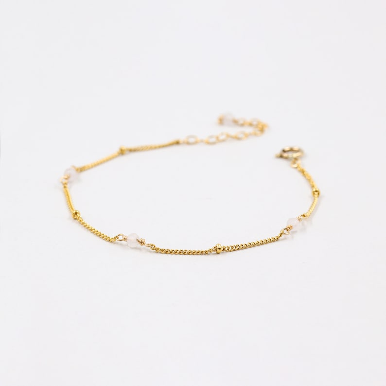 Puede incluir: Un delicado brazalete de cadena dorada con peque&ntilde;as cuentas blancas. El brazalete tiene un dise&ntilde;o sencillo y es perfecto para el uso diario.
