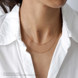 May include: Two gold necklaces with small beads, one 40 cm and one 45 cm long. Necklaces sold individually.