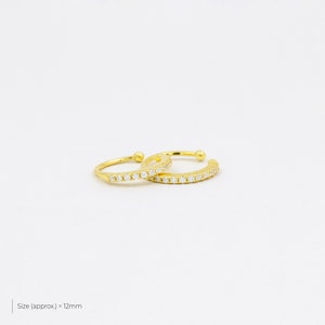 May include: Two gold ear cuffs with a row of clear cubic zirconia stones. Size (approx.) = 12mm.
