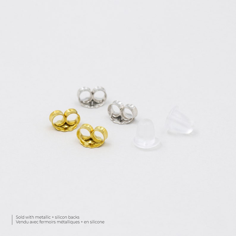May include: Four earring backs, two gold and two silver, and two clear silicone earring backs. Sold with metallic + silicon backs. Vendu avec fermoirs metalliques + en silicone.