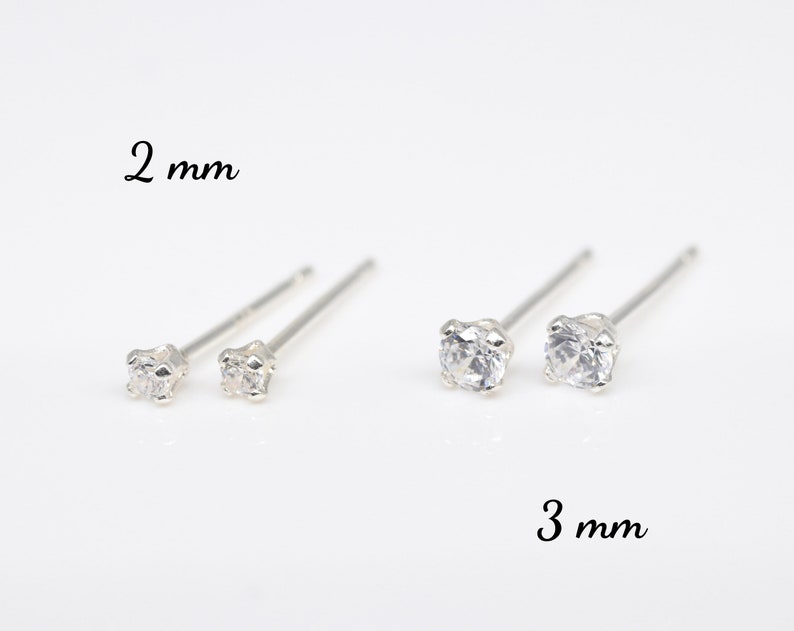 May include: Two pairs of silver stud earrings with clear cubic zirconia stones. The top pair has 2 mm stones and the bottom pair has 3 mm stones.