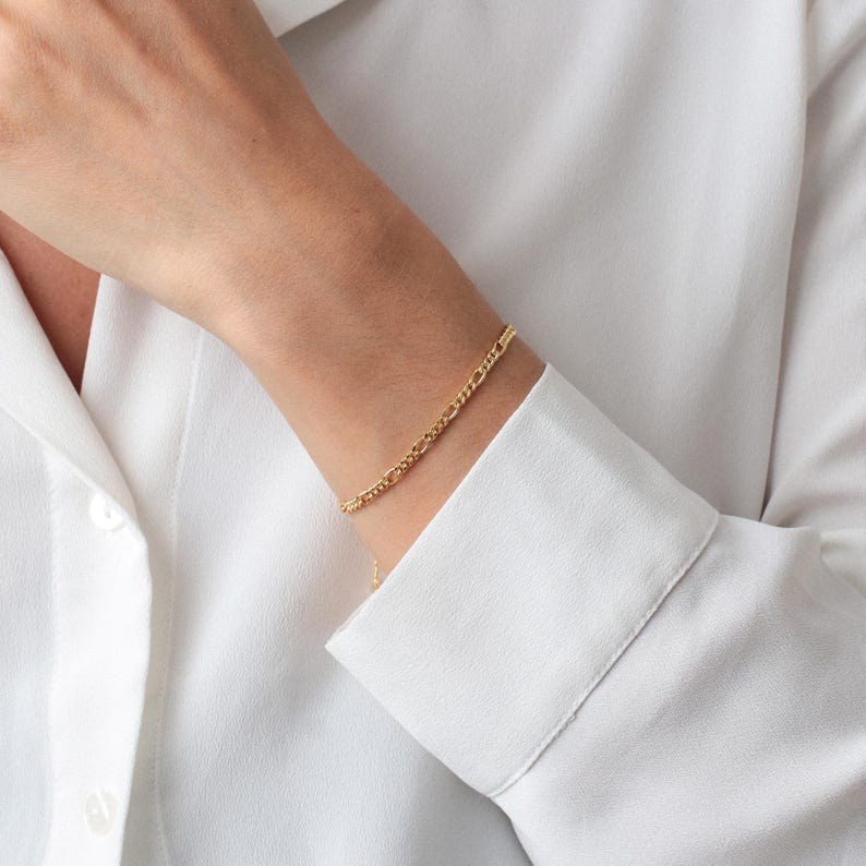 Puede incluir: Un brazalete de cadena dorada con un dise&ntilde;o delicado ligeramente texturizado. El brazalete se lleva en la mu&ntilde;eca.