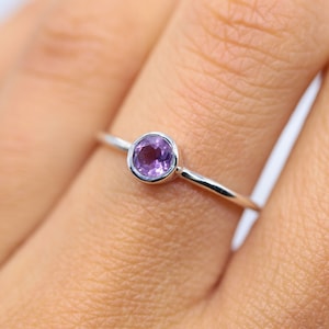 May include: A delicate silver ring with a small, round amethyst gemstone.