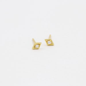 May include: A pair of gold diamond-shaped earrings with a small clear stone in the centre of each.