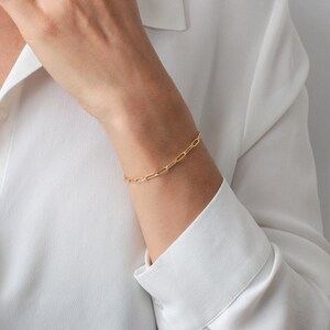 Puede incluir: Un brazalete de cadena dorada con un dise&ntilde;o simple y enlazado. El brazalete se lleva en la mu&ntilde;eca.