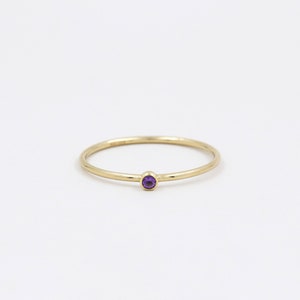 Peut inclure: Une bague simple en or avec une petite pierre d'améthyste ronde et violette.