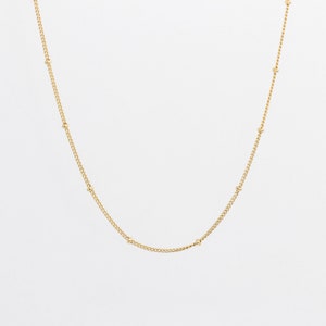 May include: A gold chain necklace with small round beads.