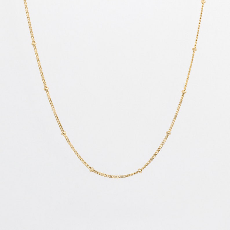 May include: A gold chain necklace with small round beads.