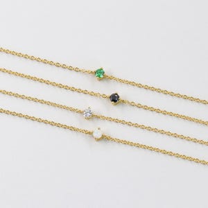 Pu&ograve; includere: Quattro delicati braccialetti a catena d'oro con un singolo accento di pietra preziosa su ciascuno. I braccialetti presentano una pietra preziosa verde, nera, bianca e opale.
