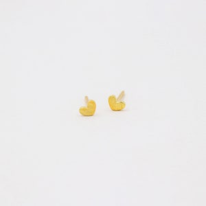 May include: A pair of gold heart-shaped stud earrings.