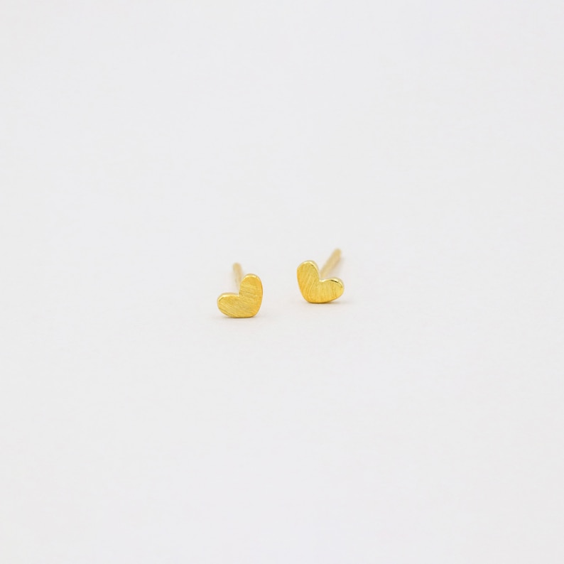 May include: A pair of gold heart-shaped stud earrings.