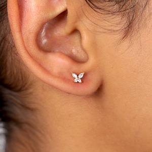 May include: A pair of gold butterfly earrings with clear cubic zirconia stones.