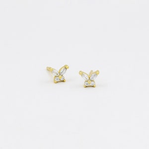 May include: A pair of gold butterfly earrings with clear cubic zirconia stones.
