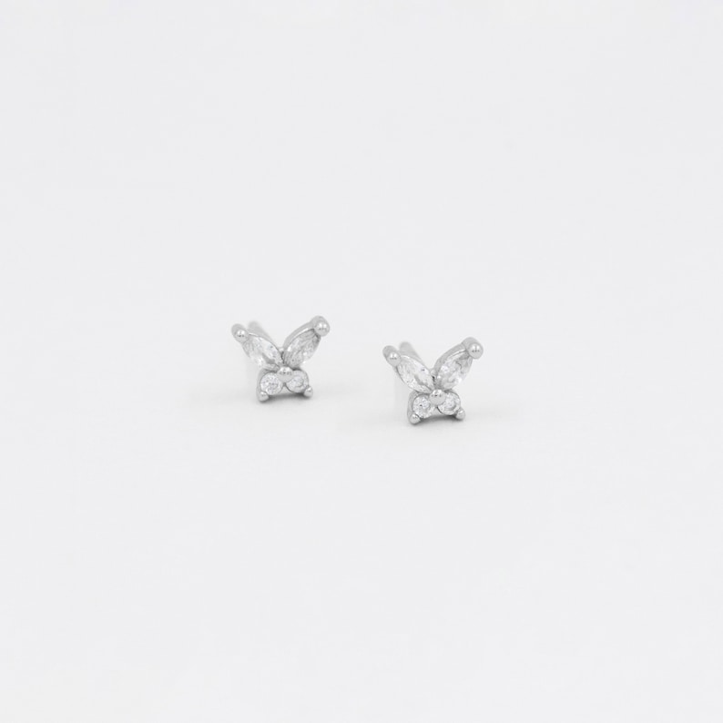 May include: A pair of silver butterfly earrings with clear cubic zirconia stones.