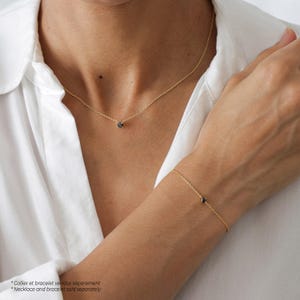 May include: A delicate gold chain necklace and bracelet with a small black gemstone pendant. The necklace and bracelet are sold separately.