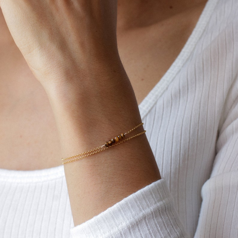 May include: A gold chain bracelet with a small cluster of tiger's eye beads.