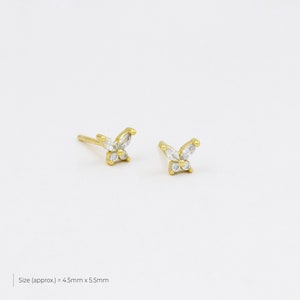 May include: A pair of gold butterfly earrings with clear cubic zirconia stones. The earrings are approximately 4.5mm x 5.5mm in size.