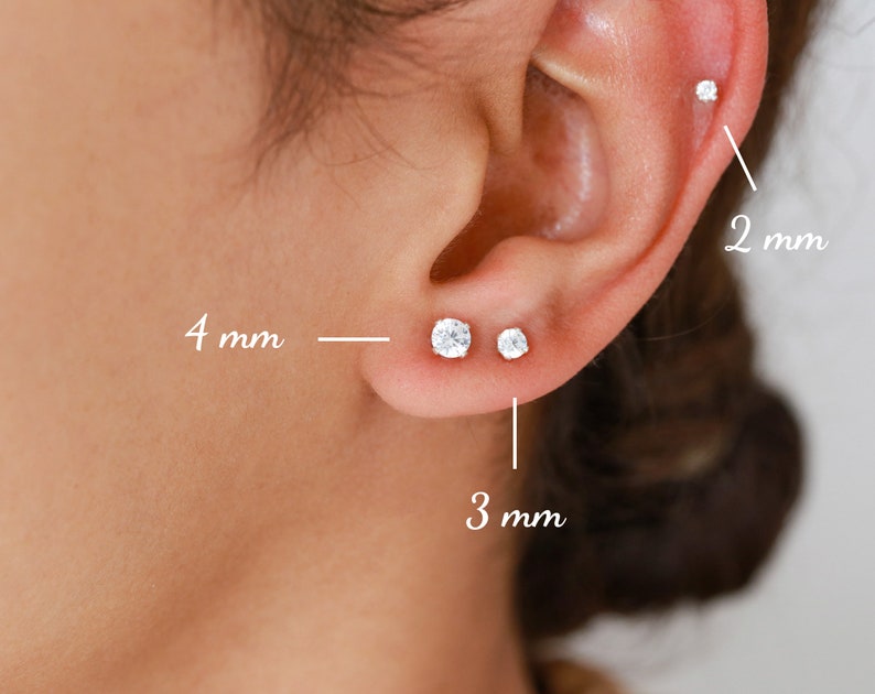 Pu&ograve; includere: Primo piano di un orecchio con tre diverse dimensioni di orecchini a perno. Gli orecchini hanno un diametro di 2 mm, 3 mm e 4 mm.