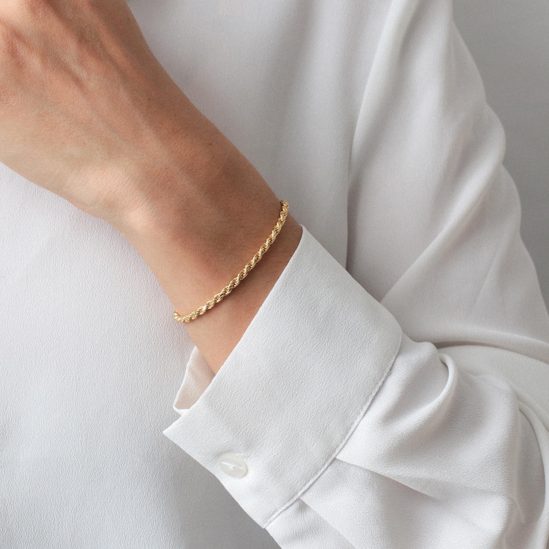 Puede incluir: Un brazalete de cadena de cuerda dorada en la mu&ntilde;eca de una persona.