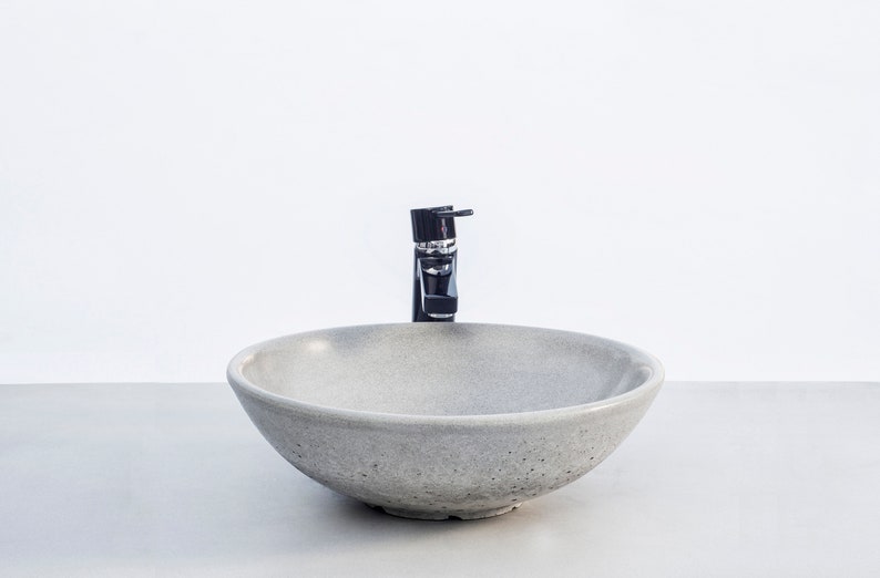 May include: A round, gray concrete sink with a black faucet.