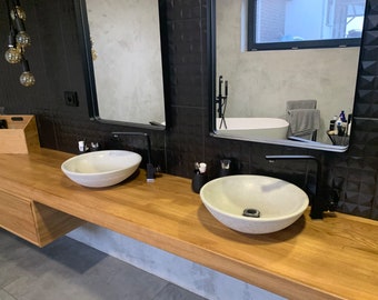 May include: A modern bathroom vanity with two white ceramic vessel sinks, black faucets, and a wooden countertop. The vanity is mounted on the wall and has a drawer below the countertop.