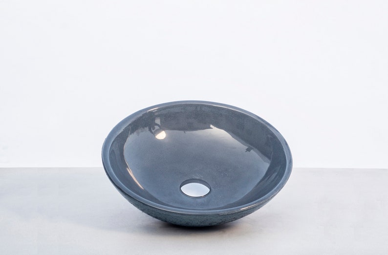 May include: A gray ceramic vessel sink with a smooth, rounded interior and a small drain hole in the center.