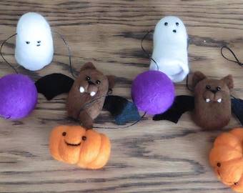 May include: A Halloween garland with felt bats, ghosts, pumpkins, and purple balls. The garland is strung together with black thread.