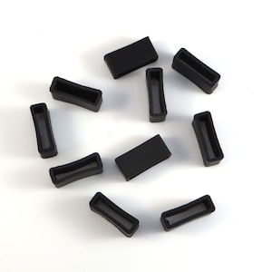 May include: Ten black rubber watch band keepers or loops. The keepers are rectangular with rounded corners.