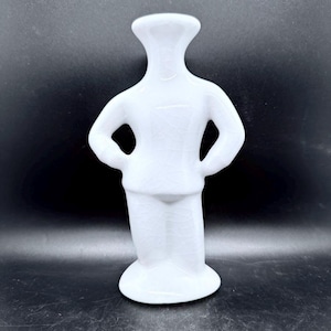 May include: A white ceramic figurine shaped like a stylized human figure with hands on hips. The surface features a distinct crackle glaze finish, creating a network of fine lines across the glossy, smooth, and solid white material of the sculpture.