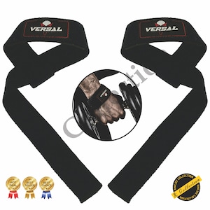 Op de afbeelding: Een paar zwarte gewichthefferslingers met het woord "VERSAL" in wit op elke slinger. De slingers zijn gemaakt van een dik, duurzaam materiaal en zijn ontworpen om je te helpen zwaardere gewichten te tillen. De slingers worden getoond met een halter op de achtergrond.