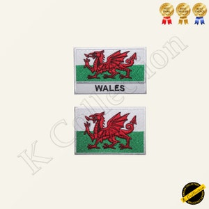 Può includere: Due toppe ricamate con la bandiera del Galles. La bandiera è rossa e bianca con un drago rosso su sfondo verde. La parola "WALES" è scritta in nero sotto la bandiera.