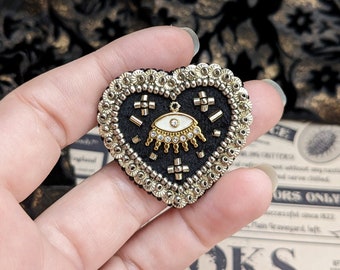 Le Fabularium Black and gold eye heart brooch in pearl and sequin embroidery