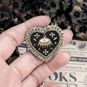 Le Fabularium Broche cœur œil noir et doré en broderie de perles et paillettes image 1