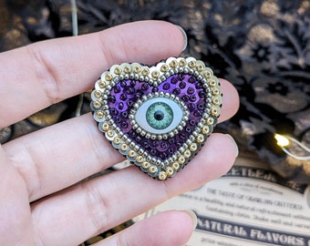 Le Fabularium Broche coeur œil paillettes violet en broderie de perles à la main | Épingle thème pastel goth | Cabinet de curiosités