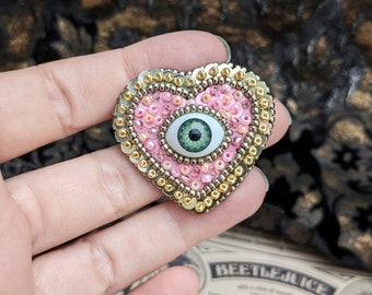 Le Fabularium Broche coeur œil paillettes rose en broderie de perles à la main | Épingle thème pastel goth | Cabinet de curiosités