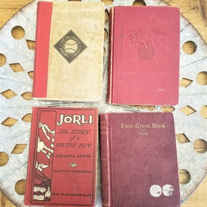 May include: Four vintage hardcover books with red covers. The books are titled "The Big League Baseball Library", "J&ouml;rli The Story of a Swiss Boy", "First Greek Book", and "First Greek Book".